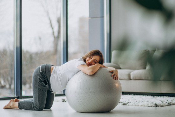 Young pregnant woman exercising yoga with fit ball at home