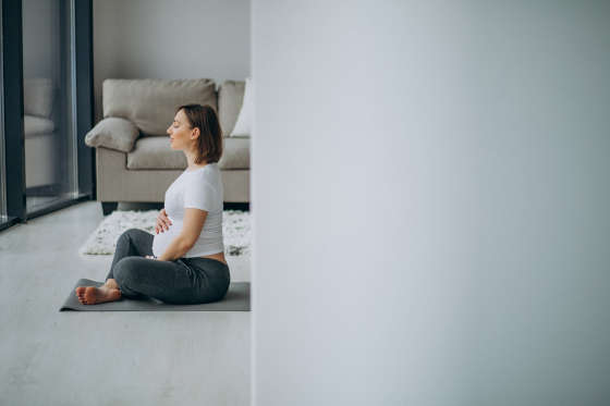 Young pregnant woman practicing yoga at home