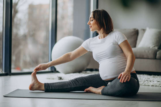 Young pregnant woman practicing yoga at home