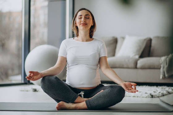 Young pregnant woman practicing yoga at home